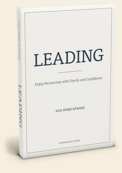 The LEADING paperback by Egil Winje Nybakk, standing at a slight angle: a cream cover with a thin brass frame, the navy title LEADING, the subtitle Enjoy the Journey with Clarity and Confidence, and the spine lettered in navy